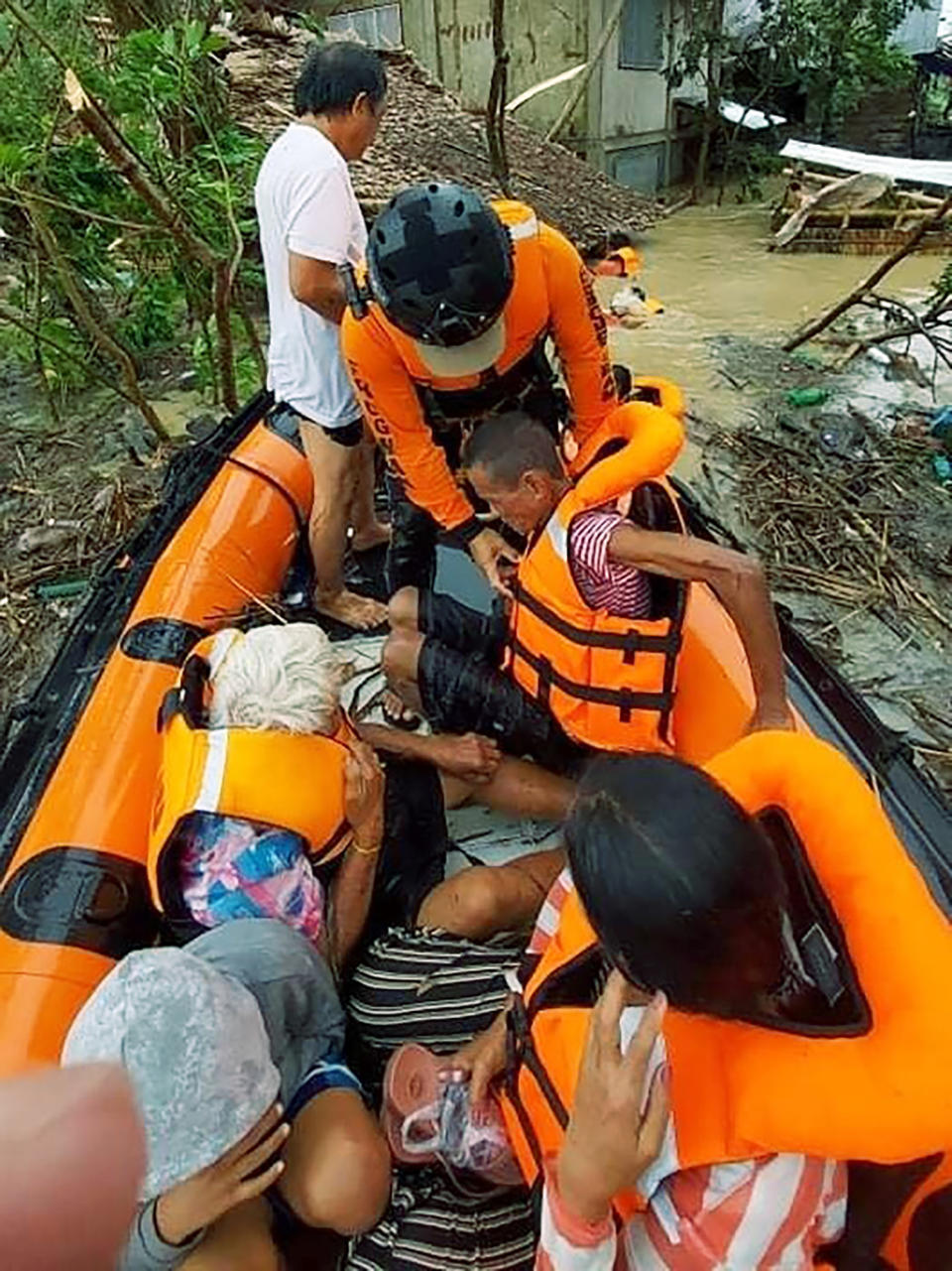In this photo provided by the Philippine Coast Guard, rescuers assist residents who were trapped in their homes after floodwaters caused by Typhoon Rai inundated their village in Negros Occidental, central Philippines on Friday, Dec. 17, 2021. The strong typhoon engulfed villages in floods that trapped residents on roofs, toppled trees and knocked out power in southern and central island provinces, where more than 300,000 villagers had fled to safety before the onslaught, officials said. (Philippine Coast Guard via AP)
