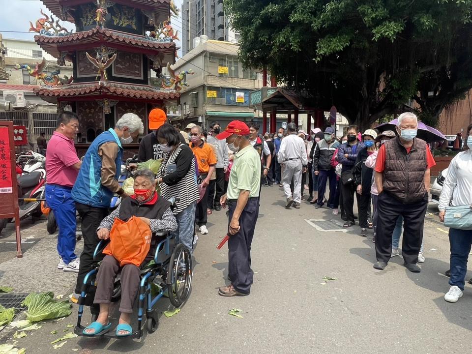 前來領取高麗菜的民眾，人龍排了一圈又一圈，即使坐輪椅也要前來分享免費領取高麗菜的小確幸。（記者彭新茹攝）