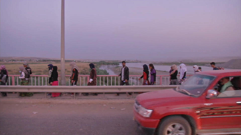 This image made from video taken on Sunday, Aug. 3, 2014 shows Iraqis people from the Yazidi community arriving in Irbil in northern Iraq after Islamic militants attacked the towns of Sinjar and Zunmar. Around 40 thousand people crossed the bridge of Shela in Fishkhabur into the Northern Kurdish Region of Iraq, after being given an ultimatum by Islamic militants to either convert to Islam, pay a security tax, leave their homes, or die. (AP Photo via AP video)