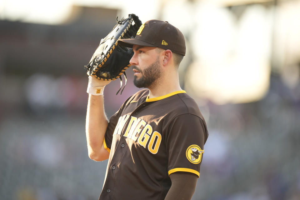 San Diego Padres first baseman Eric Hosmer uses his glove as a shield against intense sun shining on to the infield in the third inning of a baseball game against the Colorado Rockies Monday, June 14, 2021, in Denver. (AP Photo/David Zalubowski)