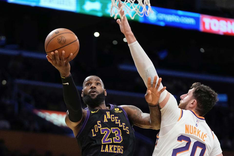 Los Angeles Lakers forward LeBron James, left shoots as Phoenix Suns center Jusuf Nurkic defends during the first half of an NBA basketball In-Season Tournament quarterfinal game Tuesday, Dec. 5, 2023, in Los Angeles. (AP Photo/Mark J. Terrill)