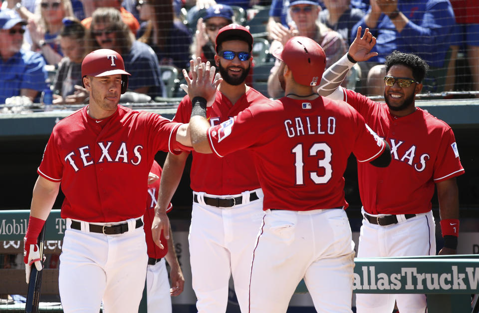 Texas Rangers' Joey Gallo (13) is congratulated by Patrick Wisdom, left, Nomar Mazara and Elvis Andrus, right, after he scored on a sacrifice fly by Hunter Pence against the Houston Astros during the first inning of a baseball game Sunday, April 21, 2019, in Arlington, Texas. (AP Photo/Mike Stone)