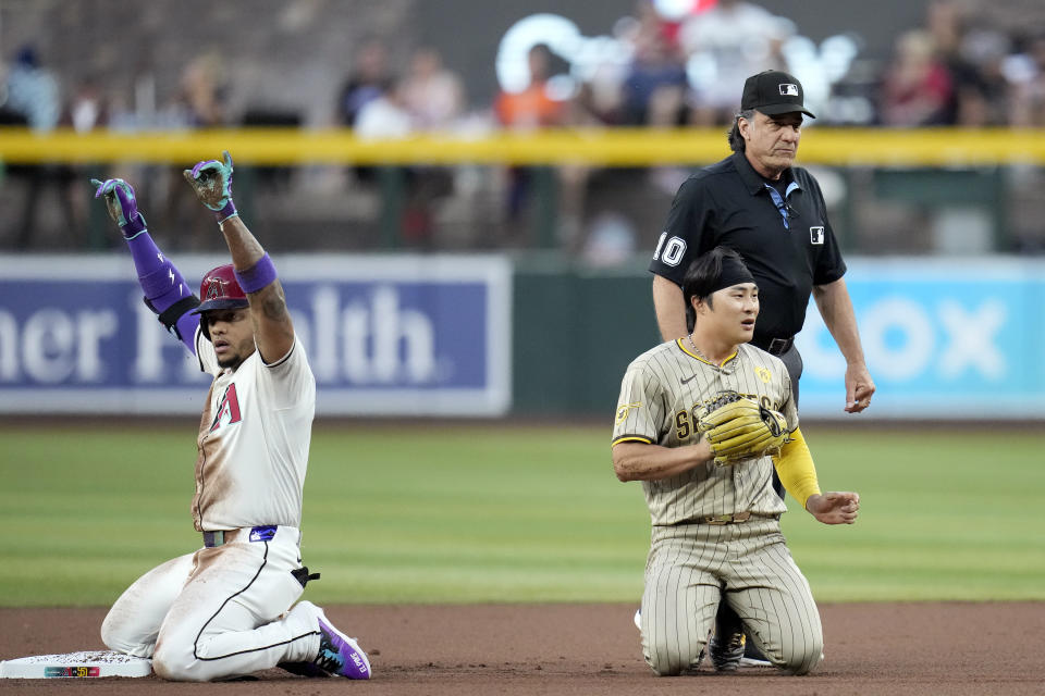 Arizona Diamondbacks' Ketel Marte, left, celebrates his double as San Diego Padres shortstop Ha-Seong Kim, front right, of South Korea, and umpire Phil Cuzzi (10) look for the baseball during the first inning of a baseball game Friday, May 3, 2024, in Phoenix. (AP Photo/Ross D. Franklin)