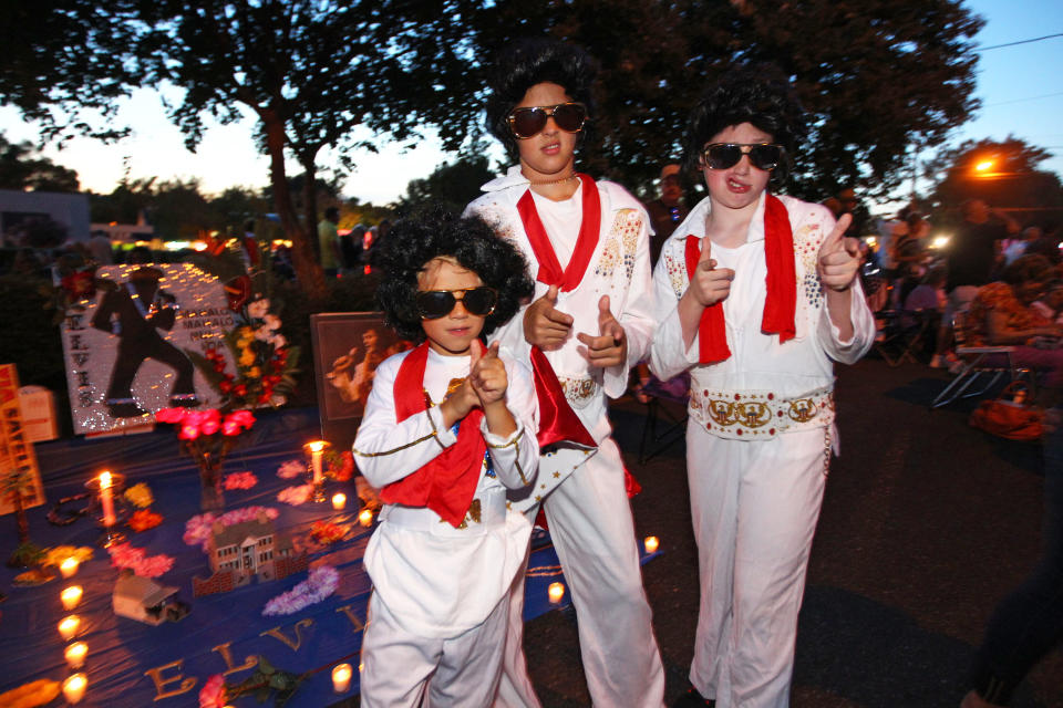 Nicholas Woodlief, 7, left, his sister Annabelle Woodlief, 11, and friend, Eli Crain, 11, right, strike an Elvis Presley pose at Graceland, Presley's home, before the annual candlelight vigil on Thursday, Aug. 15, 2013, in Memphis, Tenn. Presley fans from around the world made their annual pilgrimage to Graceland to pay their respects to the rock n' roll icon with a solemn candlelight vigil on the 36th anniversary of his death. (AP Photo/The Commercial Appeal, Nikki Boertman)