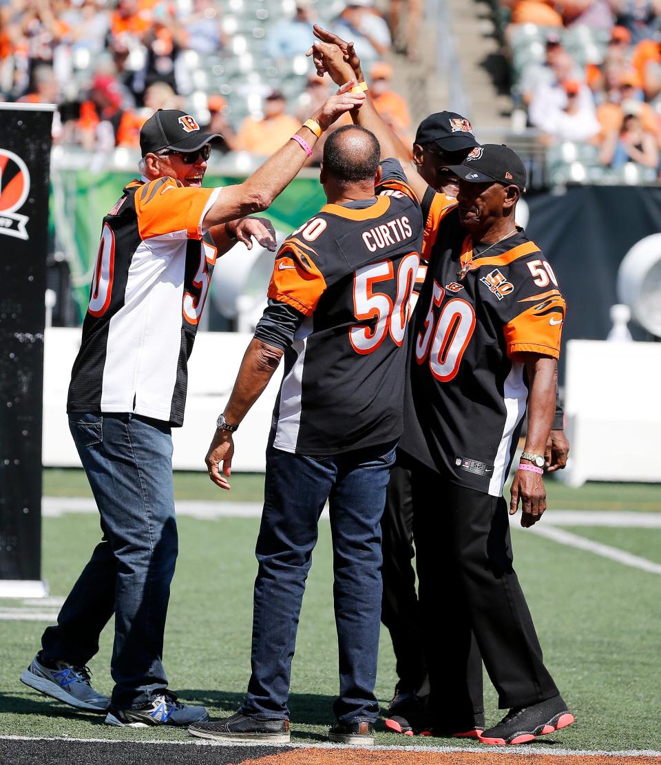 Former Bengals quarterback Ken Anderson, high-fives other former players Isaac Curtis and Lemar Parrish during halftime ceremonies in honor of the Bengals’ 50th season at Paul Brown Stadium Sunday September 10, 2017. 