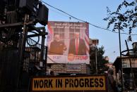 A man stands next to a hoarding with the images of U.S. President Donald Trump and India's Prime Minister Narendra Modi, ahead of Trump's visit, in Ahmedabad