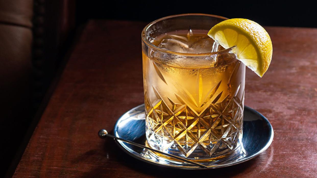 Scotch and water in a glass with ice and a lemon garnish