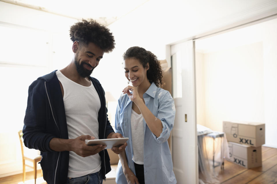 Couple moving into new home, using digital tablet