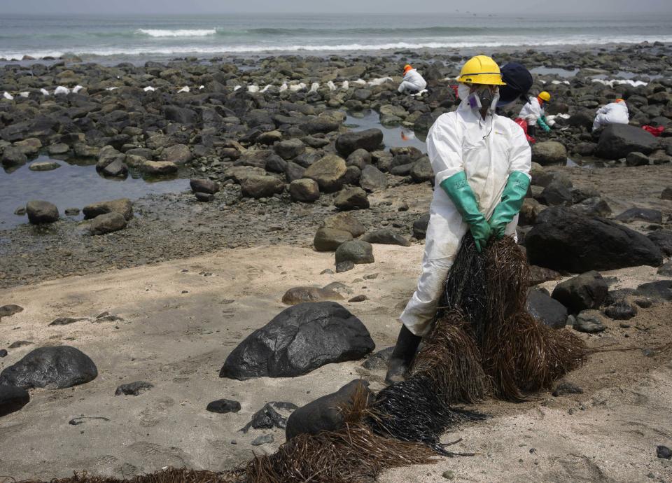 A worker holds a type of skimmer that collects oil waste during a clean-up campaign on Pocitos Beach in Ancon, Peru, Tuesday, Feb. 15, 2022. One month later, workers continue the clean-up on beaches after contamination by a Repsol oil spill. (AP Photo/Martin Mejia)