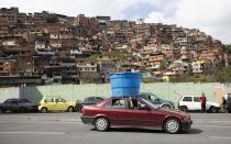 Un auto circula con un enorme recipiente de plástico con agua sobre el techo, en el vecindario humilde de Petare, en Caracas, Venezuela, el 5 de junio de 2020. Se estima que el 86% de los venezolanos reportó problemas con el suministro de agua, incluyendo un 11% que no tiene, según una encuesta realizada por la ONG Observatorio Venezolano de Servicios Públicos entre 4.500 residentes en abril. (AP Foto/Ariana Cubillos)