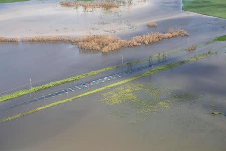 A supplied image shows three vehicles stranded on a highway flooded after Cyclone Debbie passed through the region near the township of Gunyarra, located south of the town of Bowen in Queensland, Australia, March 30, 2017. Australia Defence Force/Handout via REUTERS