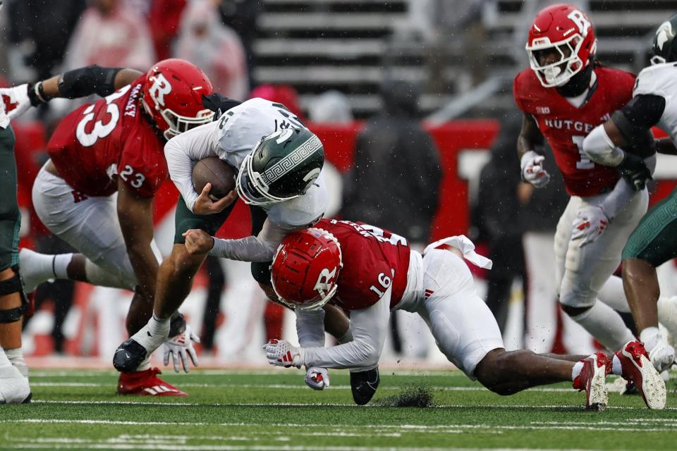 Quarterback Katin Houser of the Michigan State Spartans is tackled by defensive lineman Wesley Bailey and defensive back Max Melton of the Rutgers Scarlet Knights during the third quarter of a game at SHI Stadium on October 14, 2023 in Piscataway, New Jersey.
