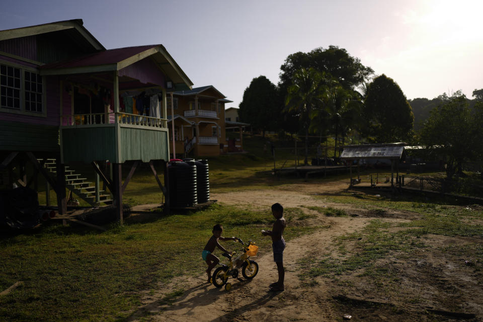 Amerindian children play with a bicycle in Chinese Landing, Guyana, Monday, April 17, 2023. Descendants of Caribs, the Amerindians living in Chinese Landing have seen their land shrink due to the Tassawini gold mining operation. (AP Photo/Matias Delacroix)