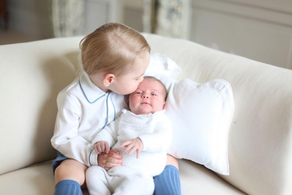 <p>Prince George gives his new baby sister a kiss on the forehead in this portrait of the siblings released shortly after Princess Charlotte's birth in 2015. </p>