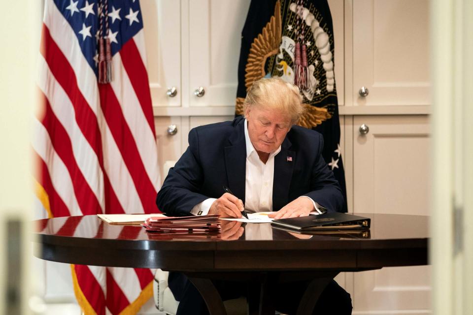 The president appears to be signing a blank piece of paper (via REUTERS)