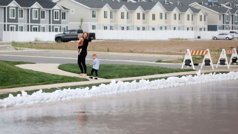 A woman and children walk near flooding in Santaquin on Wednesday, May 17, 2023.