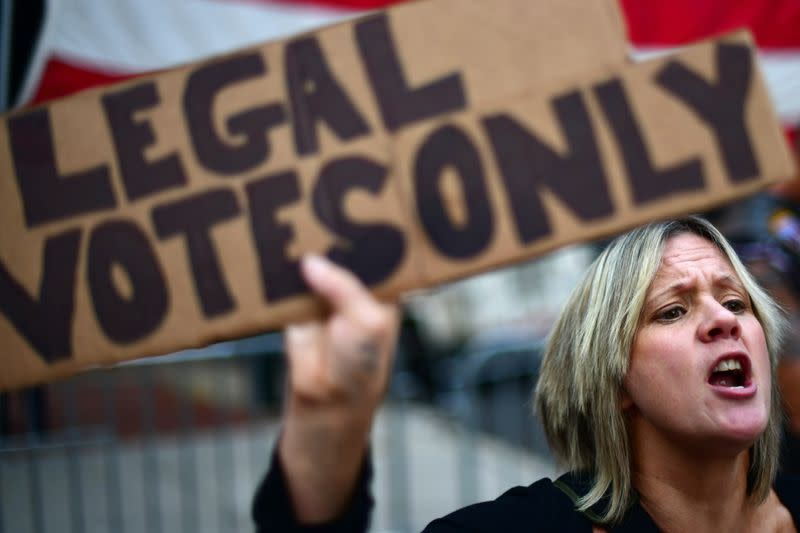 Carri Dusza, a supporter of President Donald Trump, holds a placard stating "LEGAL VOTES ONLY" while shouting across the street at supporters of President-elect Joe Biden the day after a presidential election victory was called for Biden