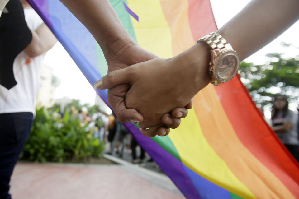 FILE - A couple holds hands as they gather for the Gay Pride rally Saturday, June 27, 2015, in Mania, Philippines. Singapore’s announcement Sunday, Aug. 22, 2022, that it would decriminalize sex between men is being hailed as a step in the right direction for LGBTQ rights in the Asia-Pacific region, a vast area of nearly 5 billion people with different laws and attitudes. (AP Photo/Bullit Marquez, File)