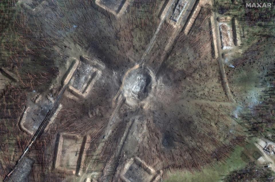 A large crater, fallen trees and destroyed train cars in a satellite image.