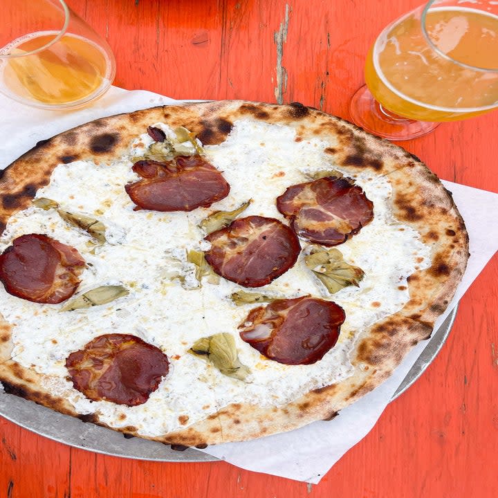 A pizza pie along with glasses containing beverages