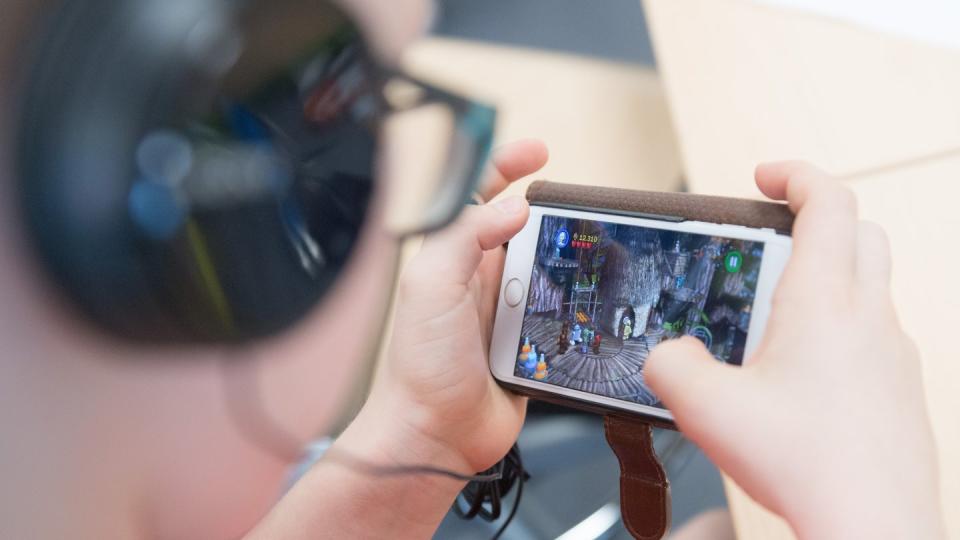 Ein Schüler spielt auf einem Smartphone ein Videospiel. Foto: Sebastian Kahnert/Illustration