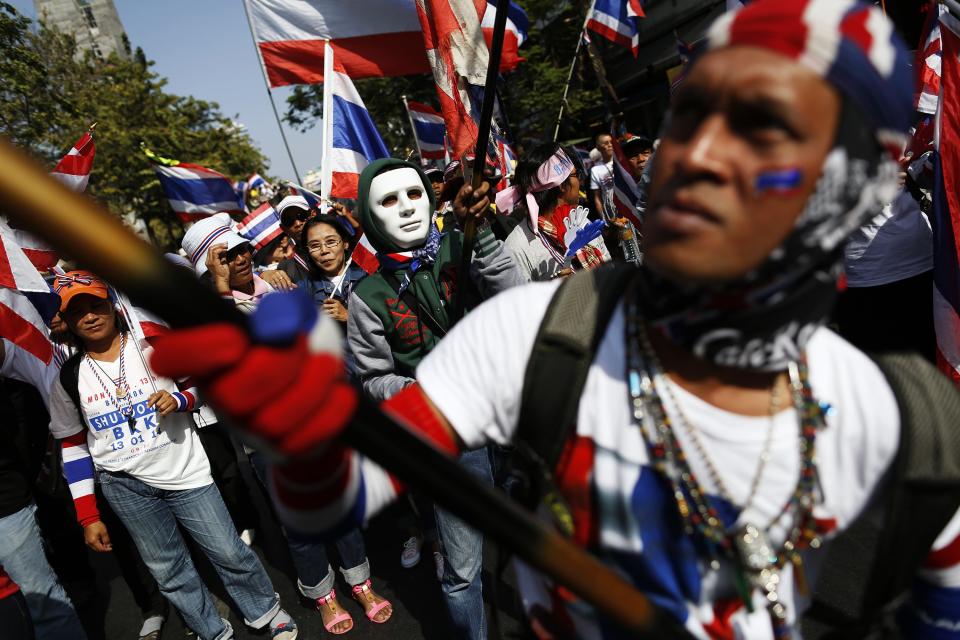 Anti-government protesters wave flags as they march through Bangkok's financial district