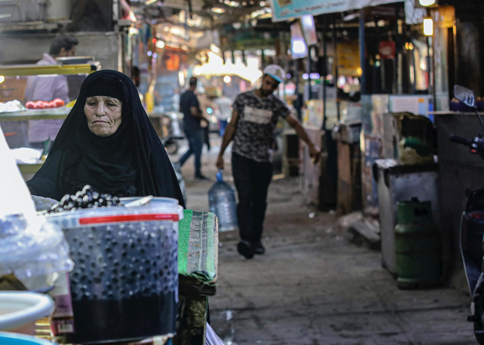 A woman street vendor waits for customers in Basra, Iraq, Wednesday, Oct. 21, 2020. Iraq is in the throes of an unprecedented liquidity crisis, as the cash-strapped state wrestles to pay public sector salaries and import essential goods while oil prices remain dangerously low. (AP Photo/Nabil al-Jurani)