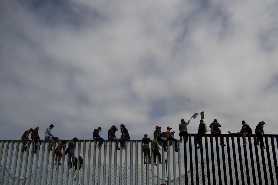 People sit on top of the border wall during the March Without Borders at Friendship Park.