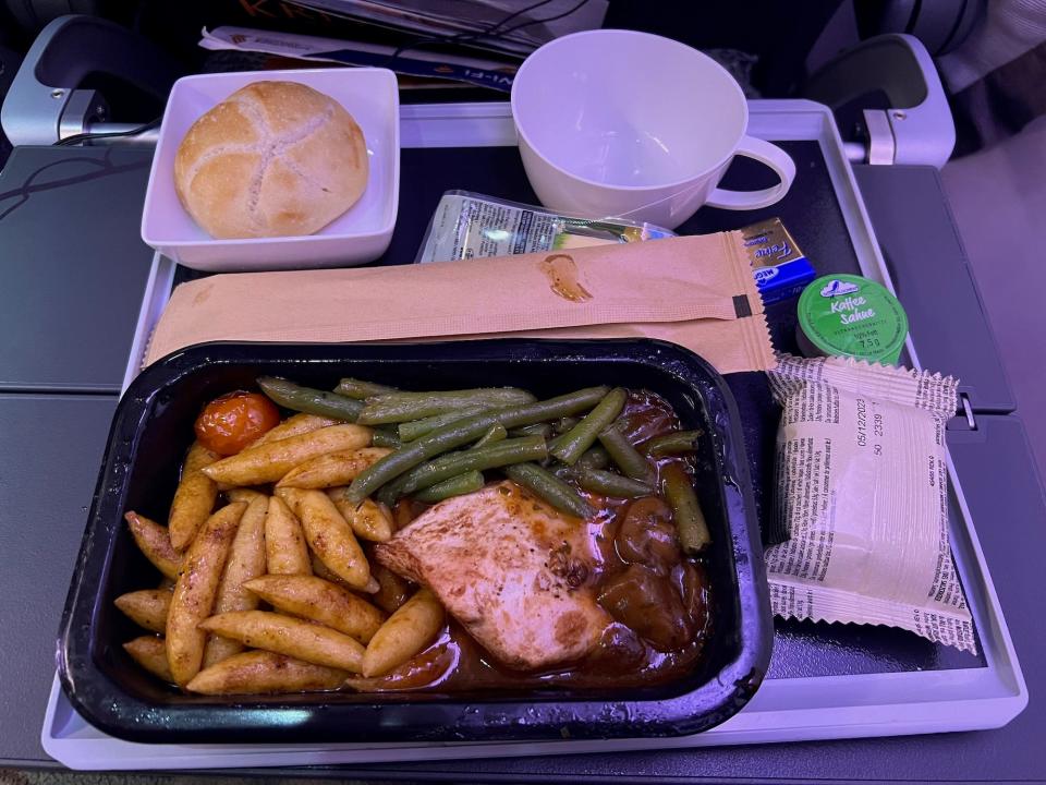 My first inflight meal — chicken, potatoes, green beans, mushrooms, bread, and a cup.