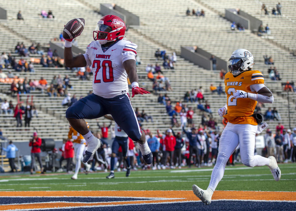 Liberty running back Quinton Cooley (20) celebrates after scoring a touchdown ahead of UTEP safety Kobe Hylton (2) during the first half of an NCAA college football game on Saturday, Nov. 25, 2023, in El Paso, Texas. (AP Photo/Andres Leighton)
