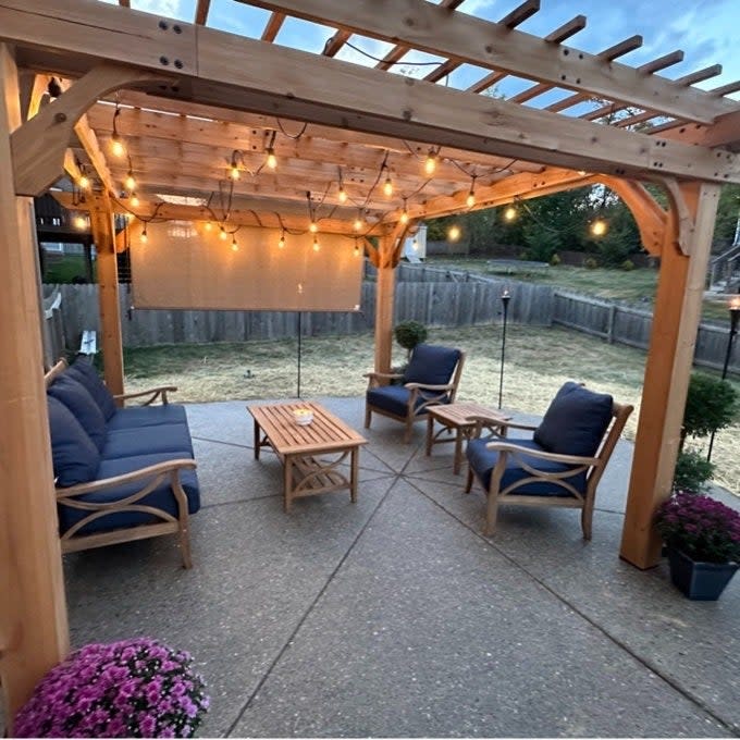 Backyard patio area with pergola, string lights, outdoor seating set, and wooden table, suitable for a shopping guide on garden furniture