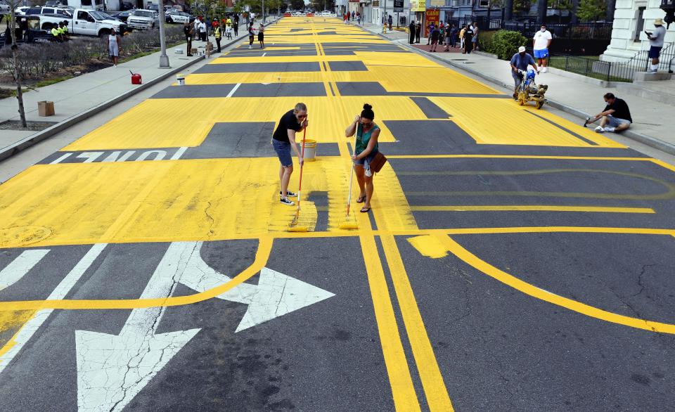 FILE - In this Sept. 4, 2020 file photo, volunteers Christine Ruth and Jenna Alcantara apply paint to a Black Lives Matter mural on Martin Luther King Jr. Boulevard in Atlantic City, N.J. Atlantic City says it will re-do the Black Lives Matter tribute because the original painting of those words across the entire street confused motorists who didn't know where to drive on it. (AP Photo/Noah K. Murray, File)