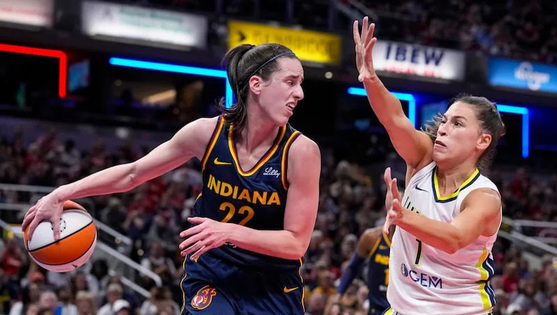 Indiana Fever guard Caitlin Clark (22) makes a behind the back pass in front of Dallas Wings guard Sevgi Uzun (1) in the second half of a WNBA basketball game in Indianapolis, Sunday, Sept. 15, 2024.