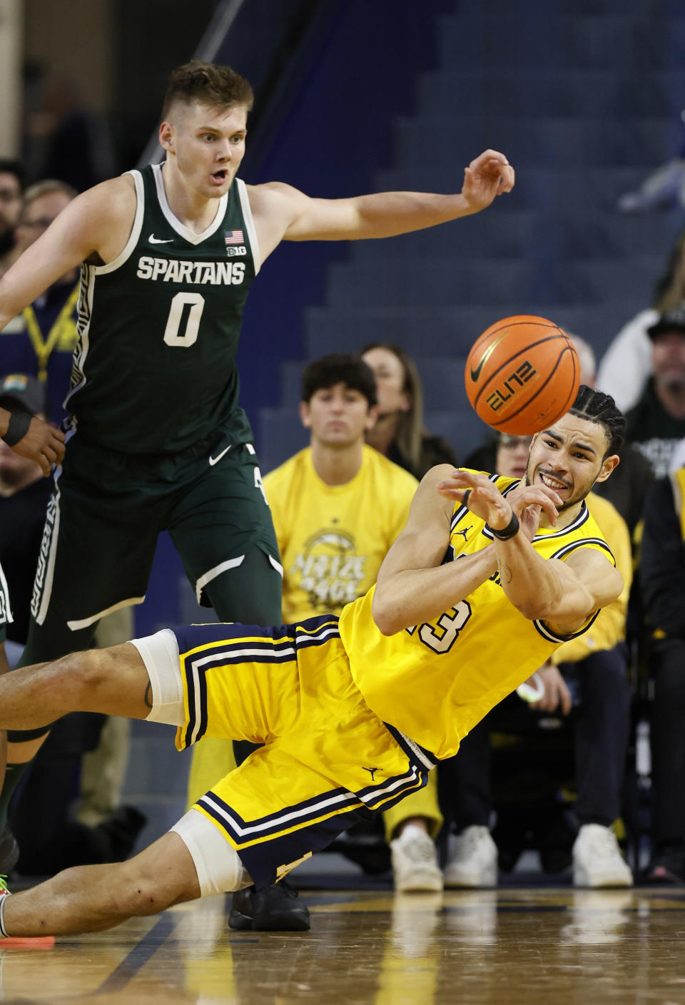 Michigan forward Olivier Nkamhoua (13) passes the ball while defended by Michigan State forward Jaxon Kohler (0) during the first half of an NCAA college basketball game Saturday, Feb. 17, 2024, in Ann Arbor, Mich. (AP Photo/Duane Burleson)