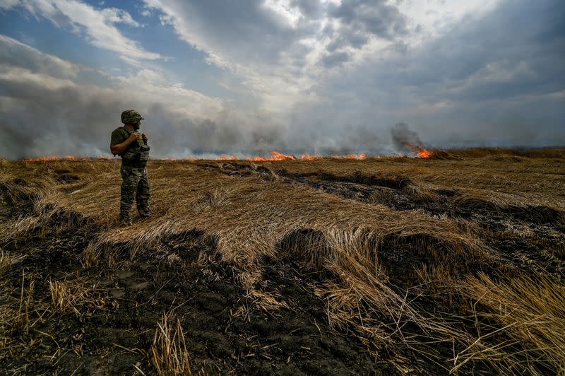 FILE PHOTO: A Ukrainian serviceman stands on a burning wheat field near a frontline on a border between Zaporizhzhia and Donetsk regions