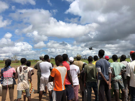 Locals watch as a helicopter lands in Guara Guara after Cyclone Idai outside Beira, Mozambique, March 22, 2019. REUTERS/Emma Rumney