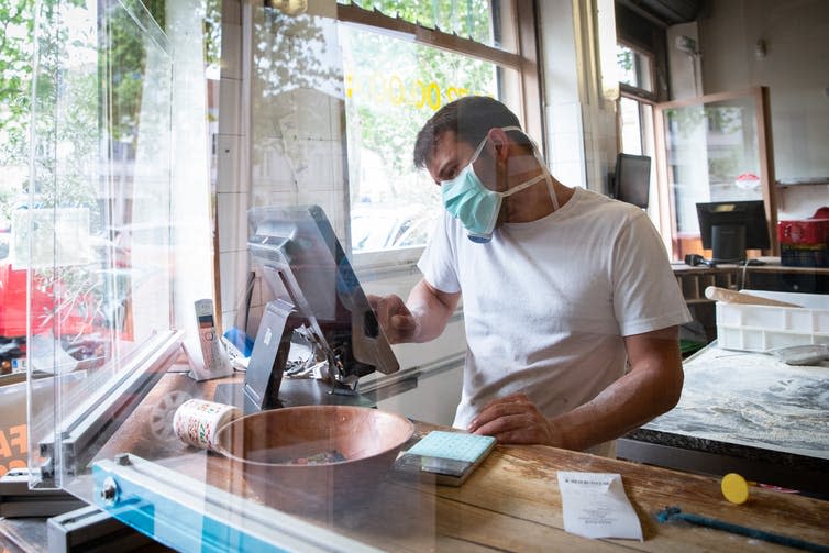 Man in restaurant behind protective screen.