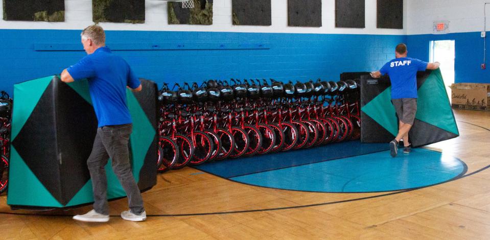 Staff members of the Boys and Girls Clubs of Polk County's James J. Musso Unit in Lakeland remove mats that were concealing the bicycles to be given away Wednesday to children in an after-school program. Can'd Aid and the Yasso Game On! Foundation gave away 100 bicycles.