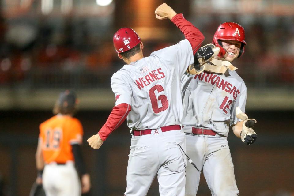 Arkansas catcher Michael Turner (12) celebrates with Arkansas first base coach Bobby Wernes after hitting a two run double in the top on the ninth inning during a NCAA Regional baseball championship game between Oklahoma St. and Arkansas at O'Brate Stadium in Stillwater, Okla. on Monday, June 6, 2022. Arkansas won 7-3 and advanced to the super regional.(Ian Maule/Tulsa World via AP)