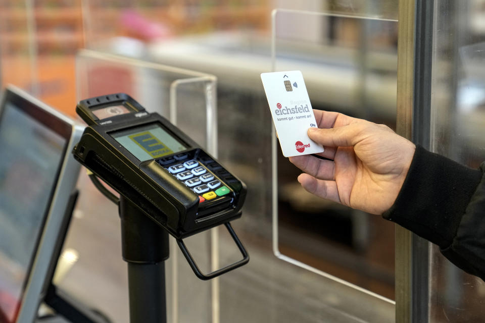 An asylum seeker pays for his purchase with a special payment card in a grocery store in Eichsfeld, Germany, Wednesday, April 24, 2024. Across Germany, cities and counties are introducing new payment cards for asylum-seekers. The new rule, which was passed by parliament last month, calls for the migrants to receive their benefits on a card that can be used for payments in local shops and services. (AP Photo/Ebrahim Noroozi)