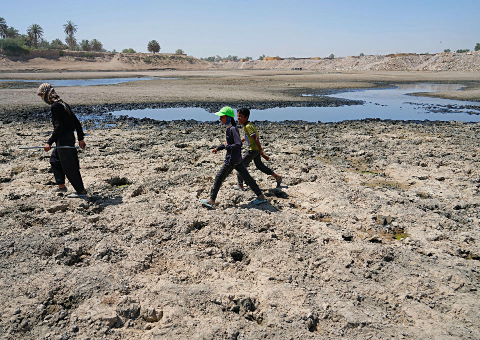 FILE - People cross the Diyala River, a tributary of the Tigris, where decreasing water levels this year have raised alarm among residents, near Baghdad, Iraq, June 29, 2022. The Middle East is one of the most vulnerable regions in the world to the impact of climate change, and already the effects are being seen. This year's annual U.N. climate change conference, known as COP27, is being held in Egypt in November, throwing a spotlight on the region. (AP Photo/Hadi Mizban, File)