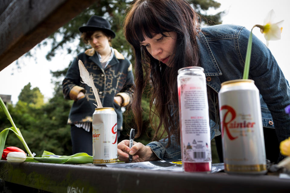 Portland residents Ashly Archibald, 26, left, and Kim Hoffman, 28, right, scrawls the quote, "who needs action when you have words?" in memory of Nirvana's lead singer, Kurt Cobain, on a bench near the home where he died on the 20th anniversary of his death Saturday, April 5, 2014, at Viretta Park in Seattle, Wash. On April 10, Nirvana will be inducted into the Rock and Roll Hall of Fame. (AP Photo/seattlepi.com, Jordan Stead) STAND ALONE PHOTO. MAGS OUT; NO SALES; SEATTLE TIMES OUT; MANDATORY CREDIT; TV OUT