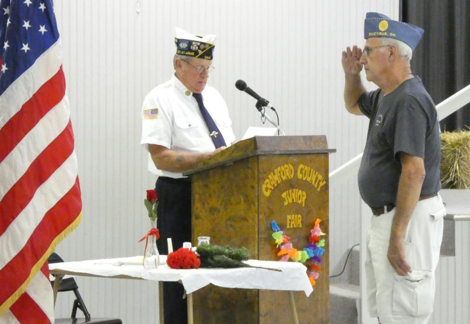 In a POW/MIA ceremony opening the 2022 bean soup supper at the Crawford County Fair, Jeff Gibson, left, speaks as Bernie Kessler of American Legion Post 181 salutes.