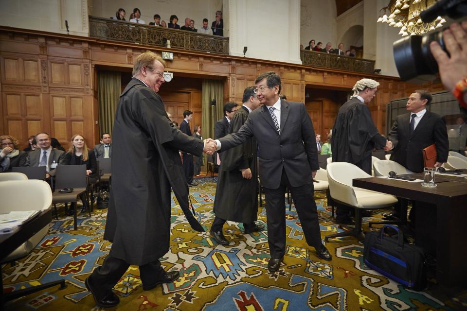 Japanese Ambassador to the Netherlands, and Chief Negotiator, Koji Tsuruoka, center, shakes hand with General Counsel of Australia Bill Campbell, left, before the International Court of Justice to deliver its verdict in The Hague, Netherlands, Monday March 31, 2014. The International Court of Justice is ruling Monday on Australia's challenge against Japan for whaling in Antarctic waters. (AP Photo/Phil Nijhuis)