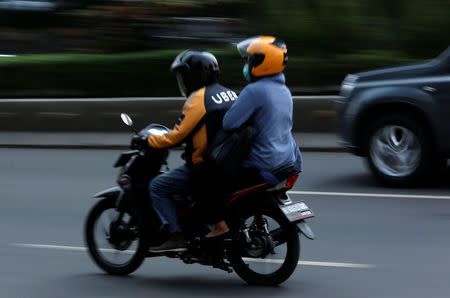 An Uber motorcycle taxi driver rides with a customer on a street in Jakarta, Indonesia September 20, 2017. REUTERS/Darren Whiteside