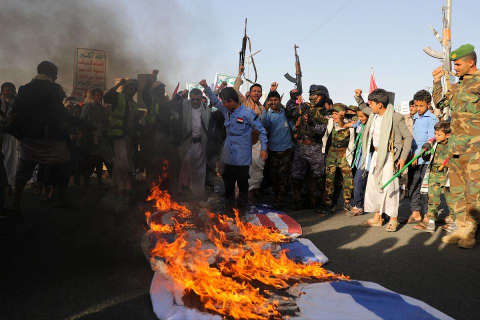 Houthi supporters in Yemen burn Israeli and US flags as they gather to denounce Western air strikes (REUTERS)