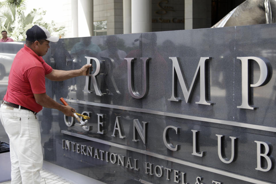 FILE - In this March 5, 2018 file photo, a man removes the word Trump, off a marquee outside the Trump Ocean Club International Hotel and Tower in Panama City. The luxury hotel that used to bear the Trump name has formally been rebranded on Tuesday, Sept. 25, after a bitter dispute over control. The 70-story, sail-shaped tower is now the JW Marriott. (AP Photo/Arnulfo Franco, File)