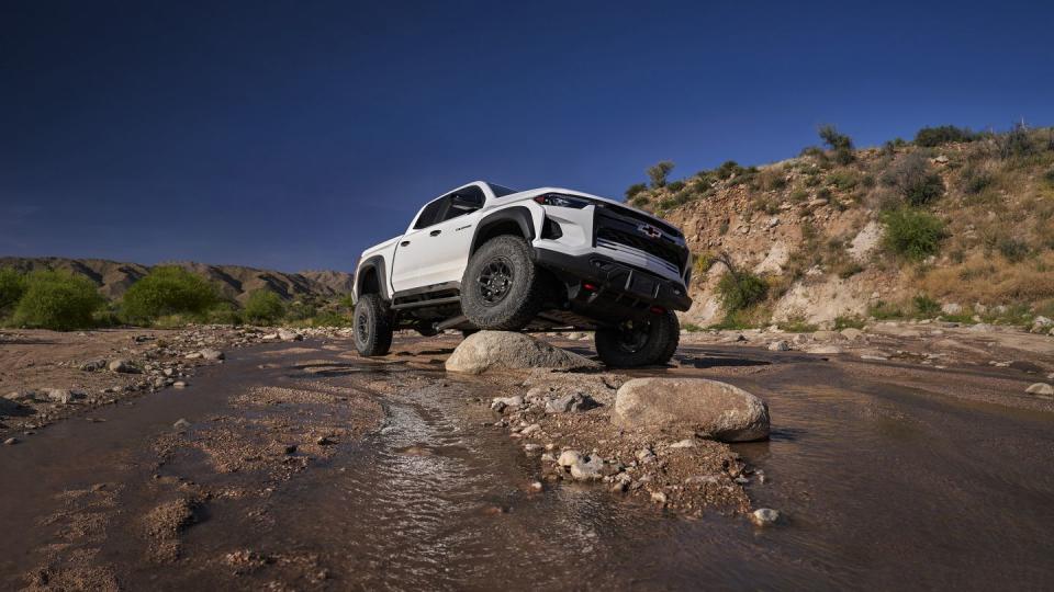 the colorado zr2 bison in a creek with front tire elevated onto a rock