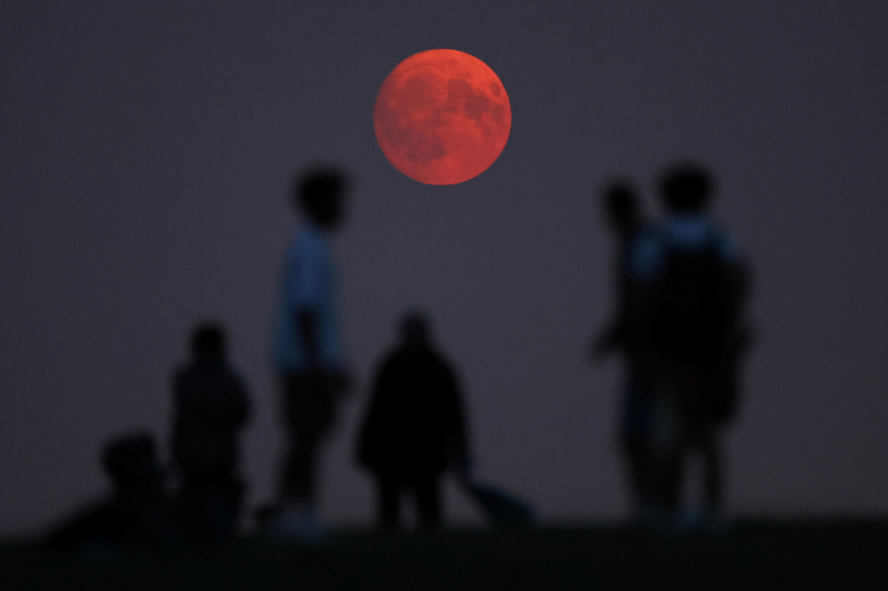 A day before the super full moon, people watch the rising moon with its red glow from smoke particles carried up in the upper atmosphere by the wildfires in North America on Parliament Hill in London, Britain, August 18, 2024. (Toby Melville/Reuters)