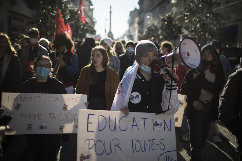 A student chants into a megaphone while holding a sign that reads "education for everyone" during a demonstration in Marseille, southern France, Tuesday Jan. 26, 2021. Teachers and university students marched together in protests or went on strike Tuesday around France to demand more government support amid the pandemic. (AP Photo/Daniel Cole)